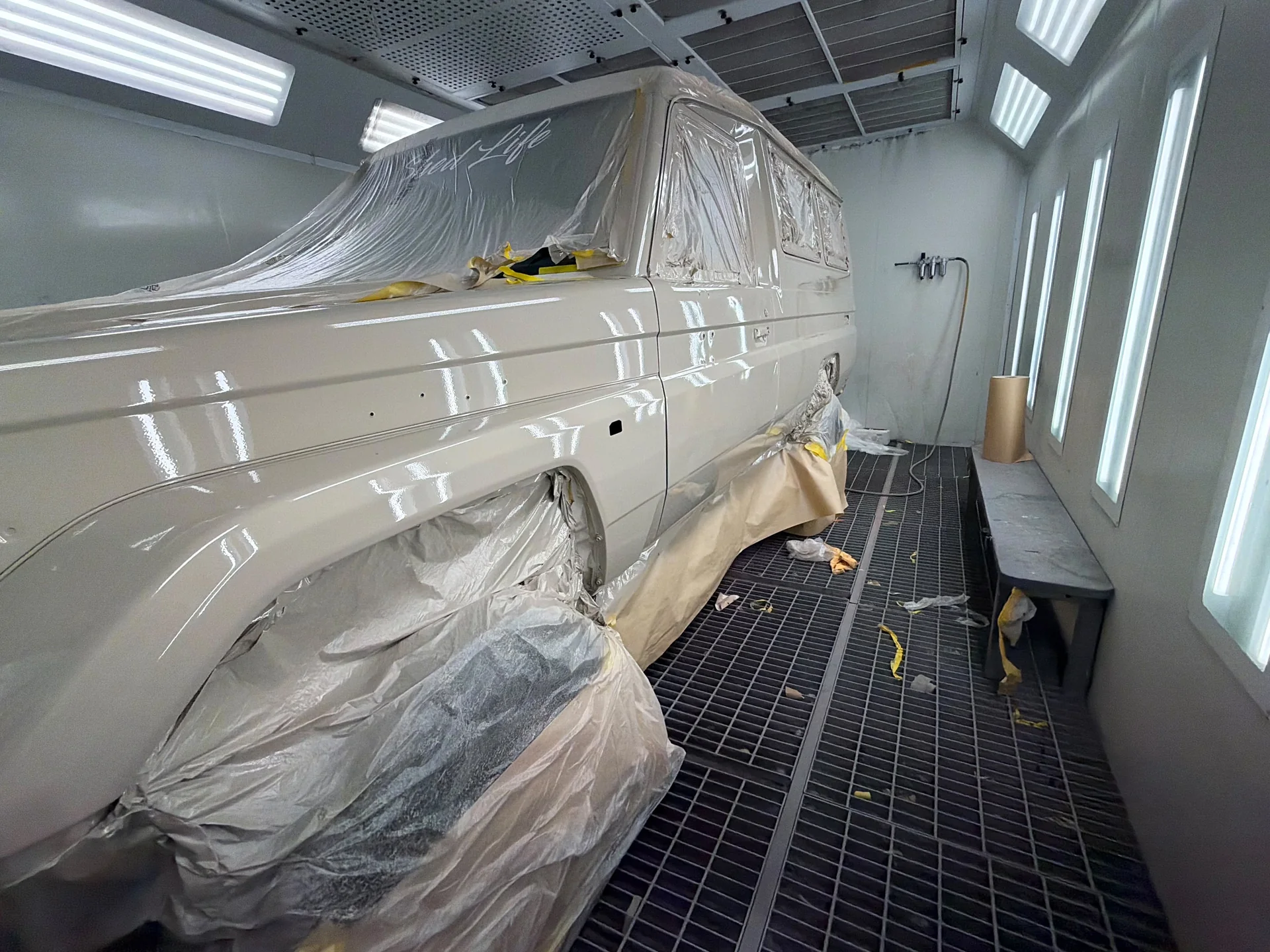 Cream 4WD with freshly painted side panels and masked windows in the spray booth