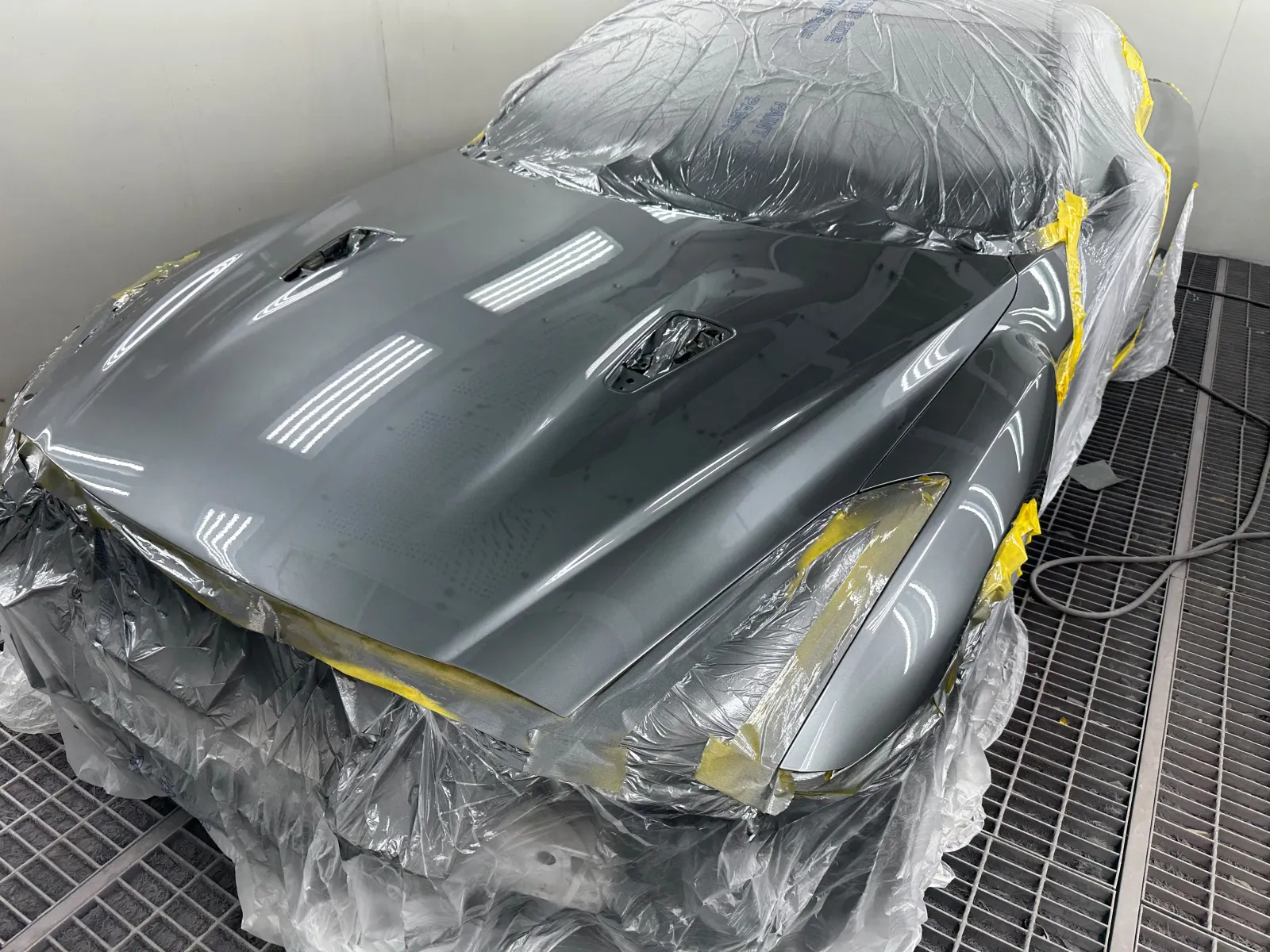 Classic sports car masked up and resprayed in metallic grey in the spray booth
