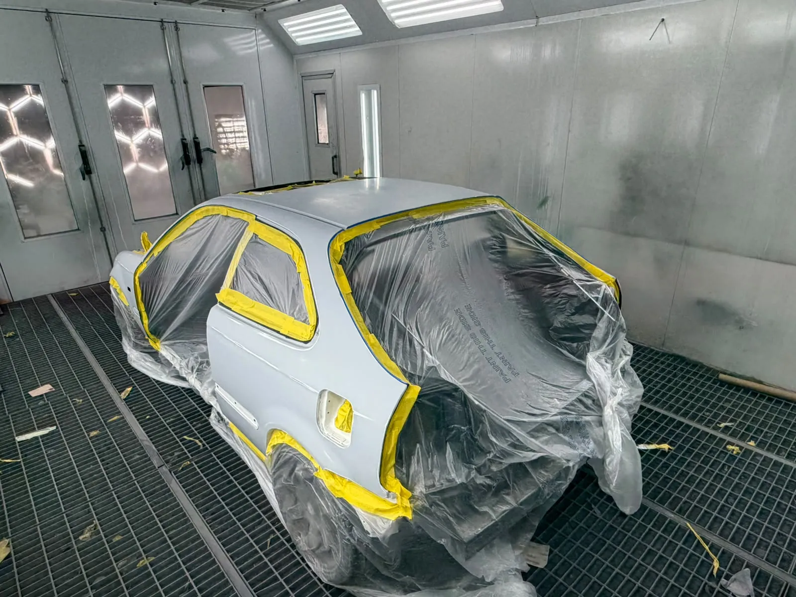 Hatchback in primer masked up in the spray booth ready for colour