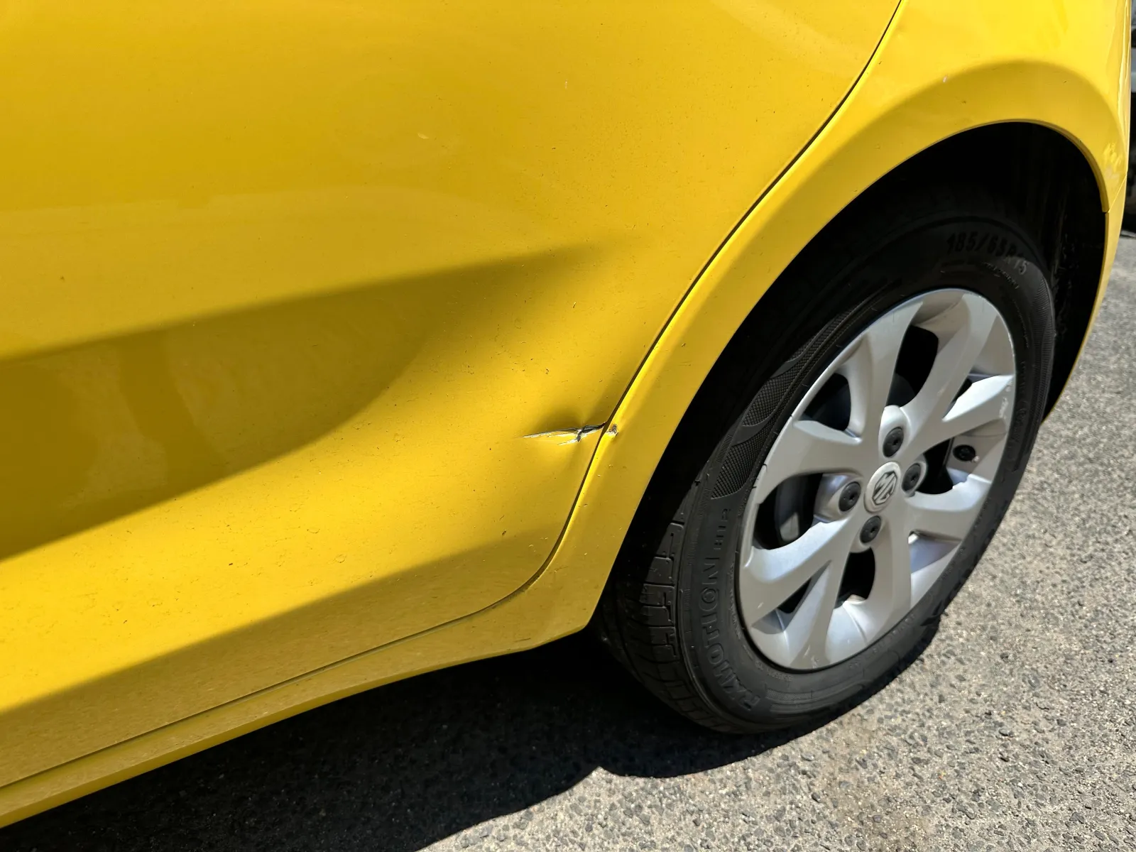 Yellow hatchback rear quarter panel with a dent before paint and panel repair