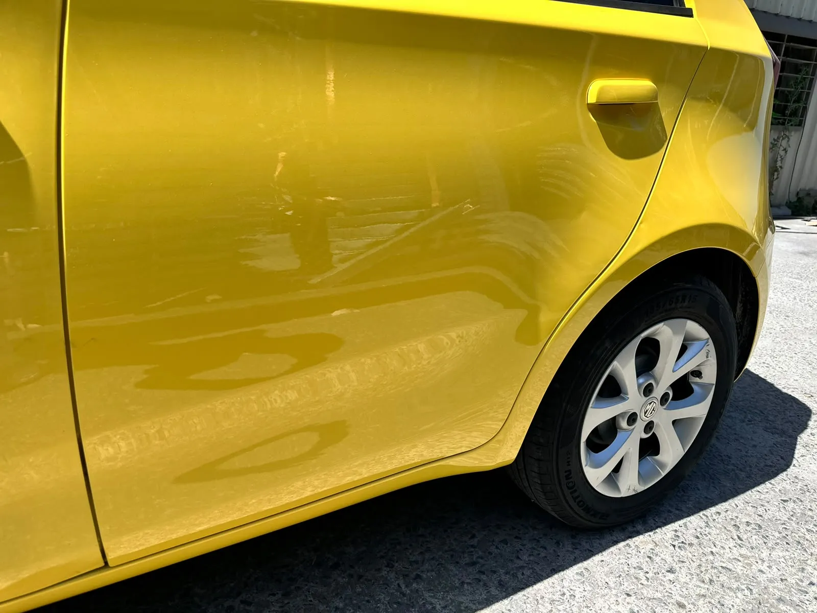 Yellow hatchback rear panel restored to a smooth gloss finish after repair